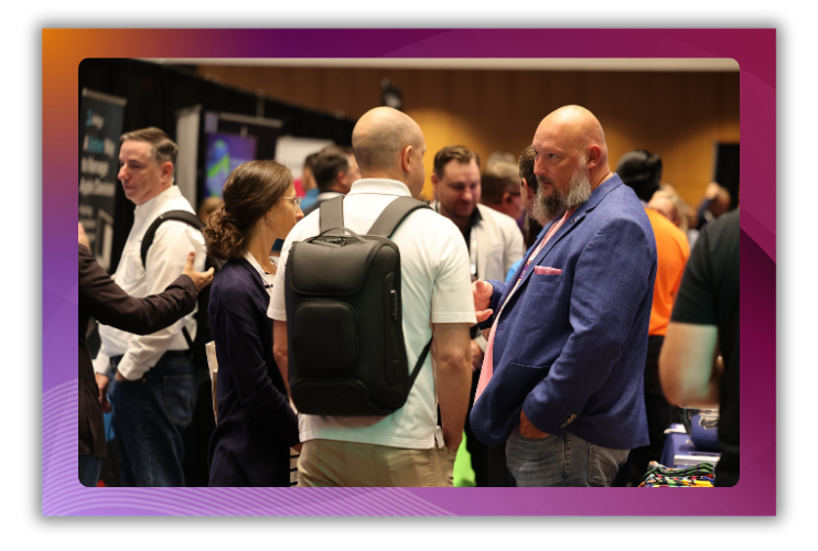 A photo of two men talking on a busy trade show floor