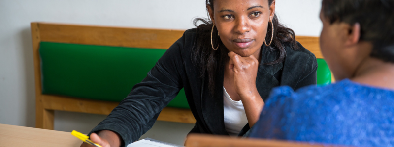 A woman looks thoughtfully at her companion while interviewing about SRHR in Tanzania.