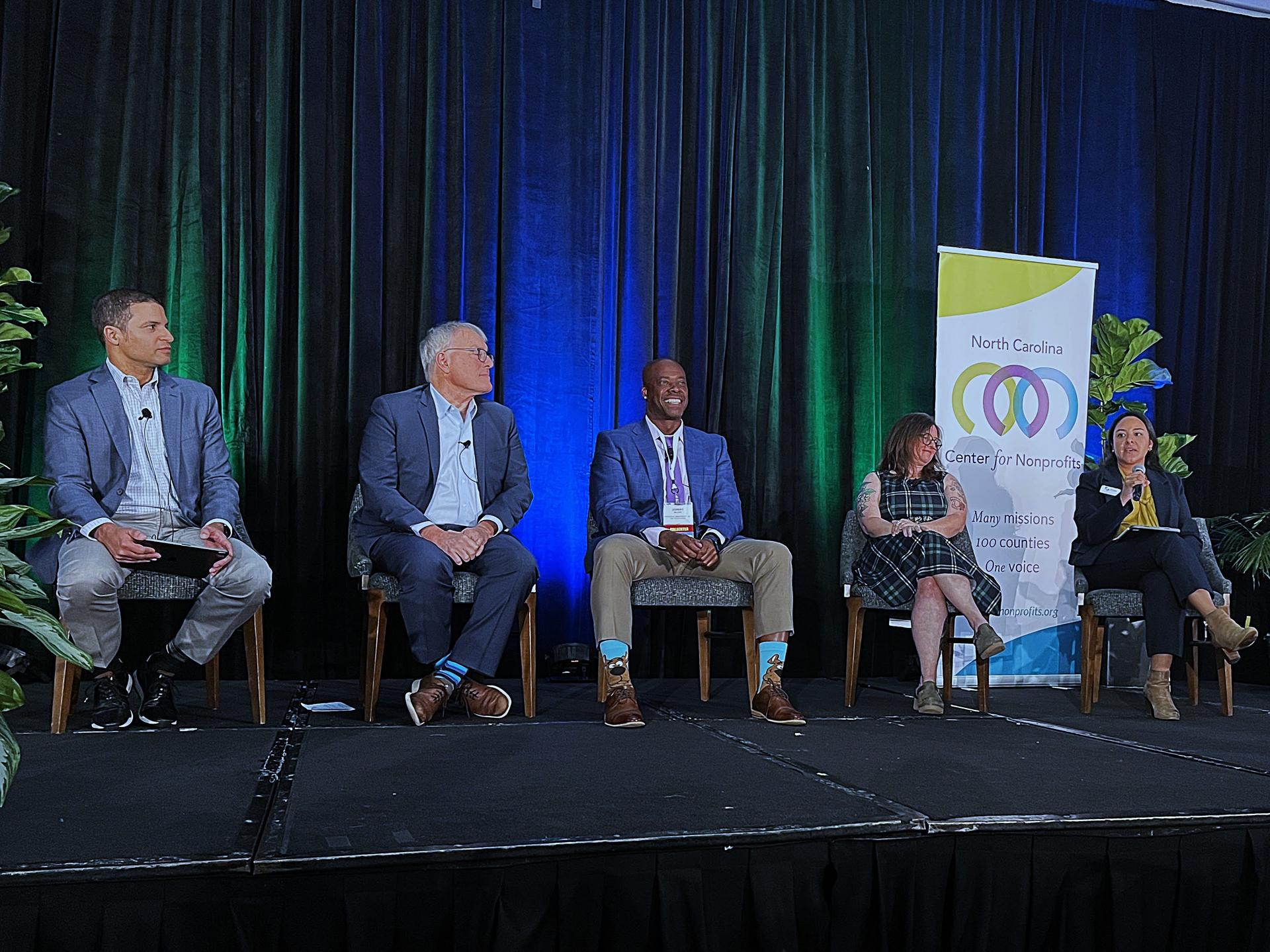 Four nonprofit and foundation panelists and the moderator sit side-by-side on stage during the conference plenary, From Challenge to Collective Strength.