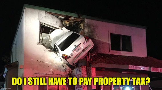A white car crashed into the second story of a building, leaving a gaping hole that the car is teetering out of.
