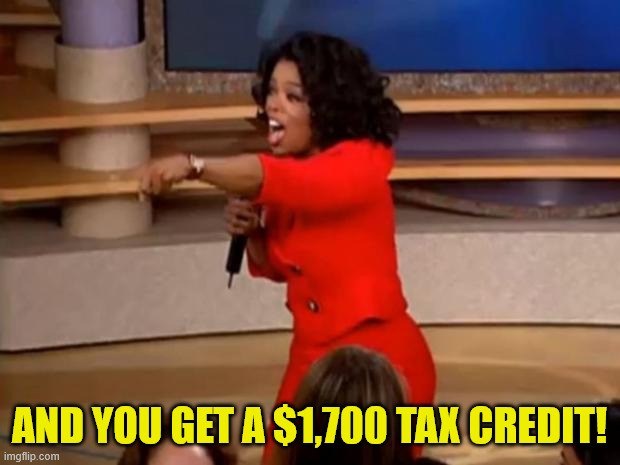 TV talk show host Oprah Winfrey standing on stage with a microphone and pointing out excitedly to the crowd. Text reads 'And you get a $1,700 tax credit!'